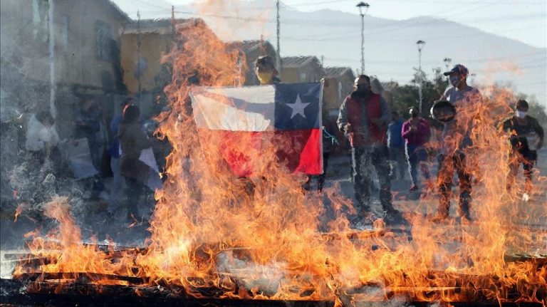 manifestante sostiene una bandera chile frente una barricada ardiendo durante una protesta santiago chile este lunes 1590427305114